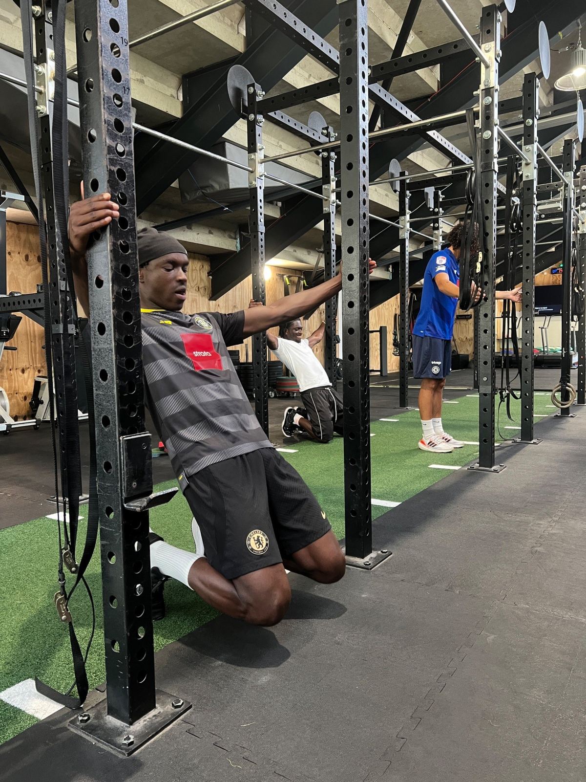 Adult footballers working on mobility and strength in a gym